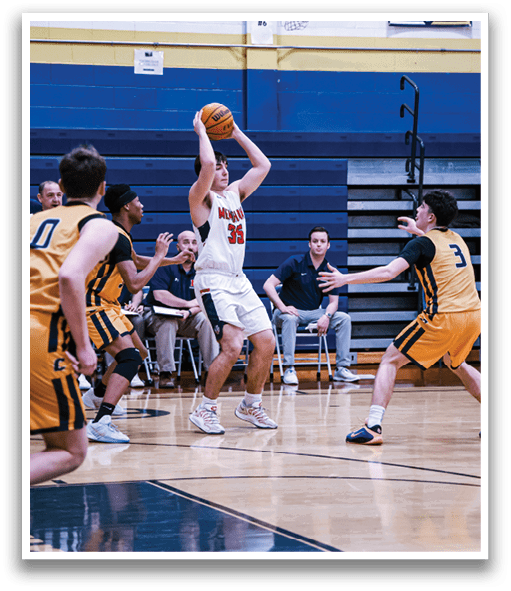 A basketball game is taking place with players on the court. One player is attempting to block a shot by another player who is holding the ball. The players are wearing uniforms and are actively engaged in the game. AI generated content