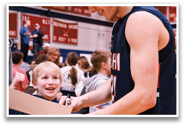 A man in a basketball uniform is signing autographs for a group of people, including a young girl. AI generated content