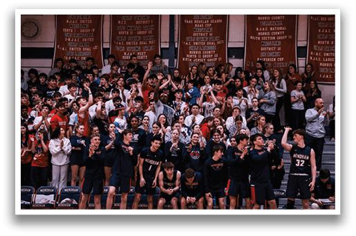 A group of people are sitting in the bleachers, watching a basketball game. They are wearing black and red clothing, and some are holding up their cell phones. AI generated content