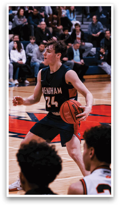 A basketball game is taking place with a group of people on the court. One player is holding a basketball while another player is trying to block him. The crowd is watching the game intently. AI generated content