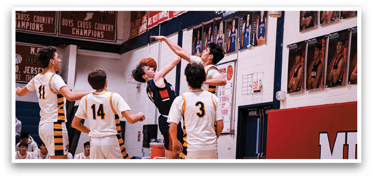 A group of basketball players are playing a game. One player is jumping to block a shot. AI generated content