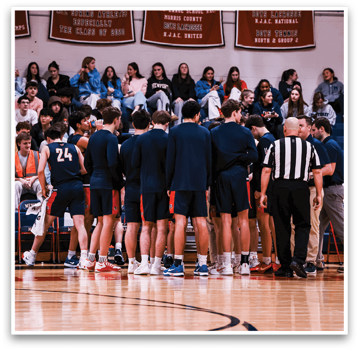 A group of basketball players are gathered on the court, with some sitting on a bench and others standing. A referee is present, overseeing the game. The players are wearing uniforms and are engaged in a conversation, likely discussing game strategies or tactics. AI generated content