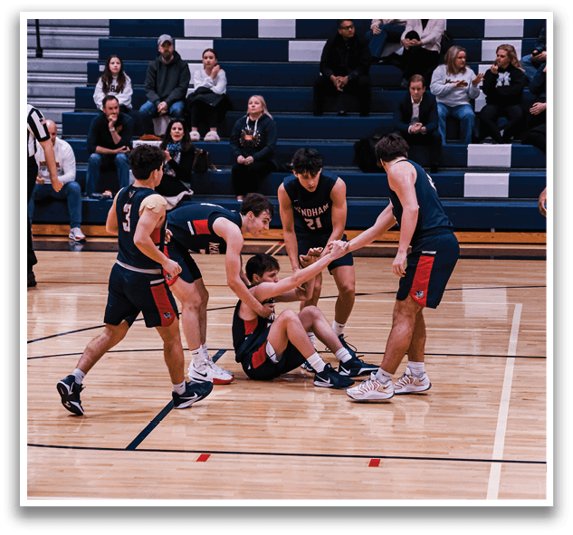 A group of men are playing basketball on a court. One man is sitting on the ground while the others are standing around him. AI generated content