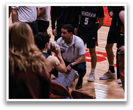 A group of people are on a basketball court, with some sitting on chairs and others standing. A man is holding a whistle, and a woman is holding a clipboard. The scene appears to be a basketball game or practice. AI generated content