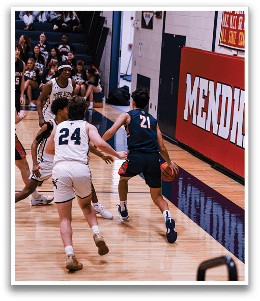 A basketball game is taking place with players on the court. A man is running with the ball while another player tries to block him. The players are wearing uniforms and the game is being played in a gym. AI generated content