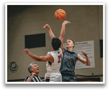 Two men are playing basketball, with one jumping in the air to block a shot. The other player is trying to get past the defender. The basketball is in the air, and the players are focused on the game. AI generated content