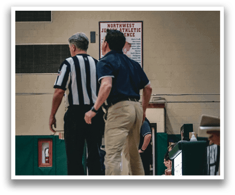 Two men in a gym, one wearing a referee shirt, the other wearing a blue shirt. AI generated content