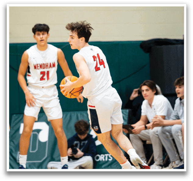 Two basketball players are on the court, one holding a ball and the other with a basketball in his hand. They are both wearing shorts and white shirts. There are also several other people in the scene, some of whom are sitting on a bench. AI generated content