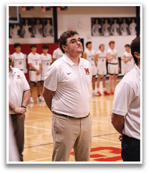 A man wearing a white shirt and tan pants stands on a basketball court. AI generated content