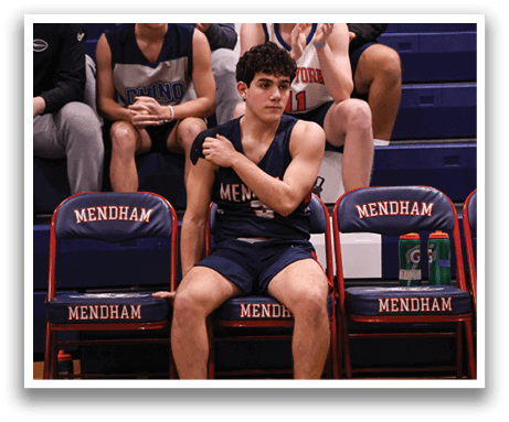 A boy sits on a bench with his legs crossed, wearing a basketball uniform. AI generated content