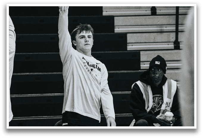 A man stands in a gym, holding his arm up, while another man sits on a bench. AI generated content