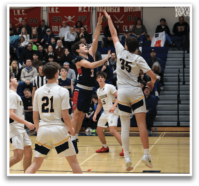 A basketball game is in progress with two teams playing. One player is attempting to block a shot by the opposing team. The crowd is watching the game intently. AI generated content