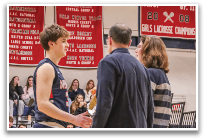 A man and woman are talking to a boy in a gym. The boy is wearing a blue and red uniform. AI generated content