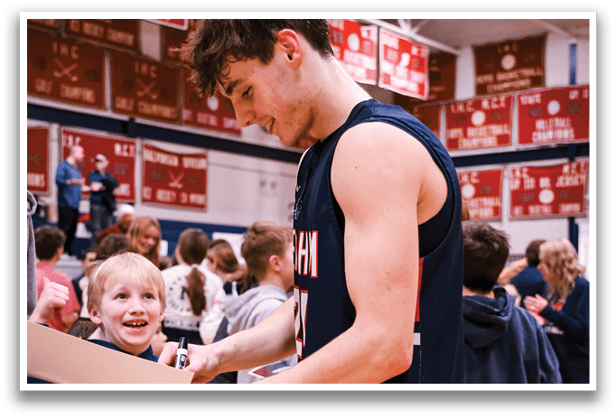 A man in a basketball uniform is signing autographs for a group of people, including a young girl. AI generated content