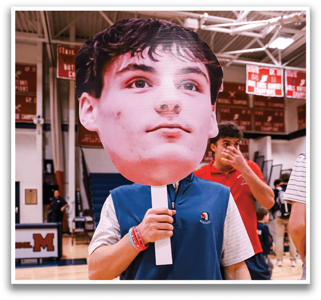 A man holds a giant cardboard cutout of his face while standing on a basketball court. AI generated content
