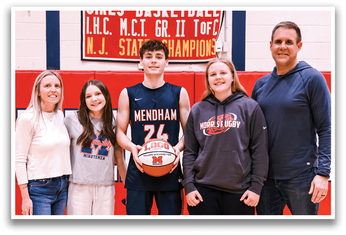 A group of people, including a man holding a basketball, pose for a photo in a gym. AI generated content