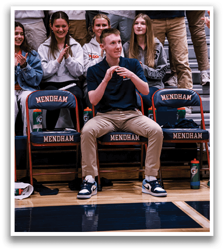 A man is sitting on a chair in a stadium, surrounded by a crowd of people. AI generated content