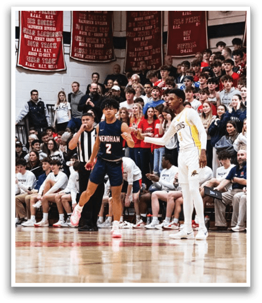 A basketball game is taking place with a crowd of people watching. Two basketball players are on the court, one of them wearing a blue uniform. The players are shaking hands, and there are several other people in the scene, including some sitting on chairs. AI generated content