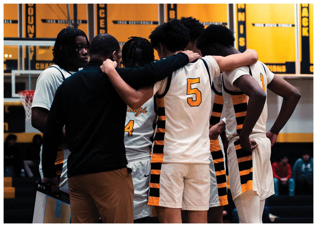 A group of basketball players huddle together on the court, with one player wearing a yellow jersey. Contenido generado con IA