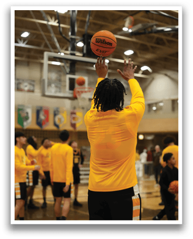A group of people are playing basketball in a gym. One person is holding a basketball and getting ready to throw it. Contenido generado con IA