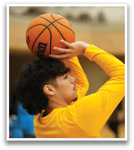 A man in a yellow shirt is attempting to shoot a basketball. Contenido generado con IA