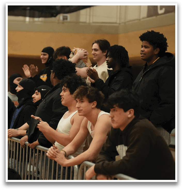 A group of people are sitting on a fence, watching a game. Some of them are wearing masks. Contenido generado con IA