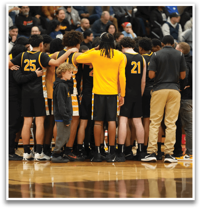 A group of people, including children, are huddled together on a basketball court. Contenido generado con IA