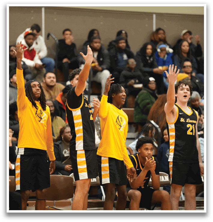 A group of young men are on a basketball court, with some of them holding up their hands in the air. The crowd is watching the game, and there are several chairs placed around the court. Contenido generado con IA