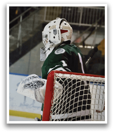 A hockey player wearing a green jersey and white pads is standing in front of a net. AI generated content