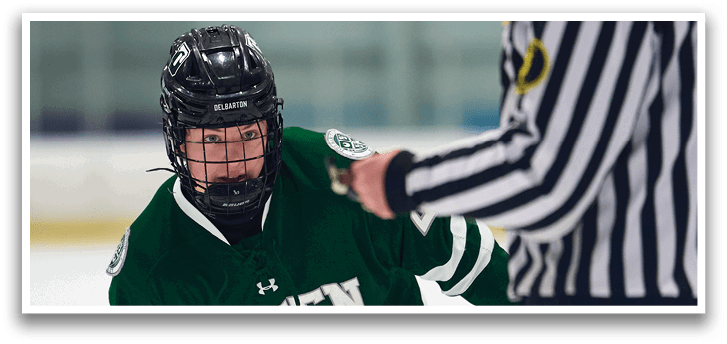 A hockey player is on the ice, holding a stick, and wearing a helmet. The referee is standing behind him, watching the play. AI generated content
