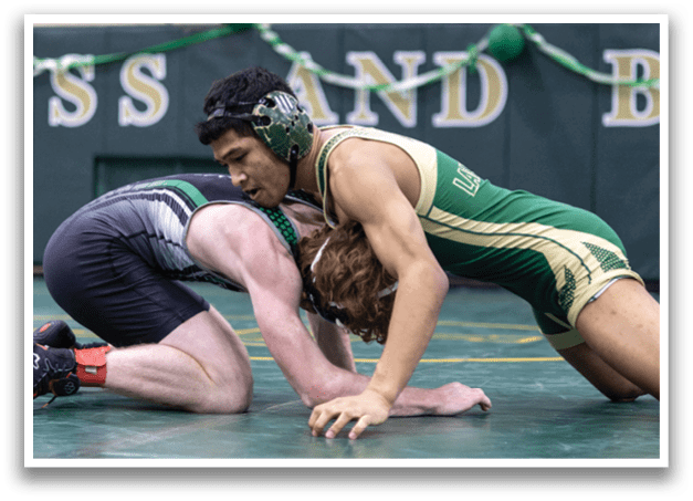Two wrestlers are on the ground, one with a green and white uniform and the other with a gray and black uniform. The wrestlers are grappling with each other, possibly during a match. AI generated content