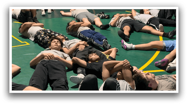A group of people are lying on the floor in a gym, doing exercises. AI generated content