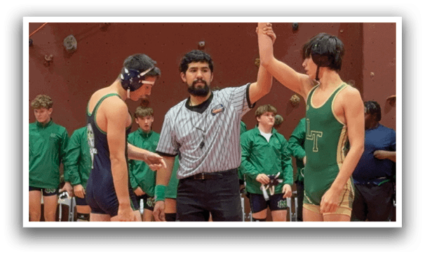 Two men are wrestling in a ring, with one man holding up his hand in victory. A referee is present, overseeing the match. The wrestlers are wearing green and blue uniforms. AI generated content