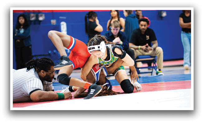 A wrestling match is taking place with a man on the ground and a woman on top of him. The woman is wearing a black shirt and a green headband. AI generated content