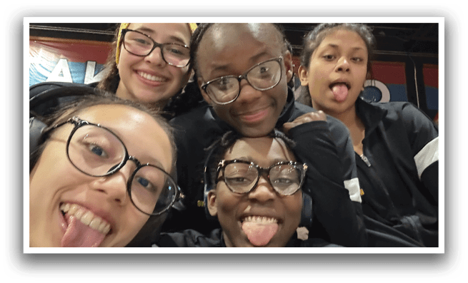 Four girls wearing glasses and black jackets pose for a picture. AI generated content