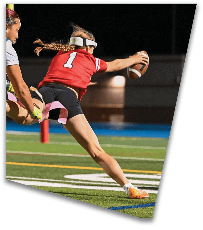 A person wearing a dark football uniform and helmet with “American Canyon" on the jersey is kneeling on one knee on a field at night. Description generated by AI