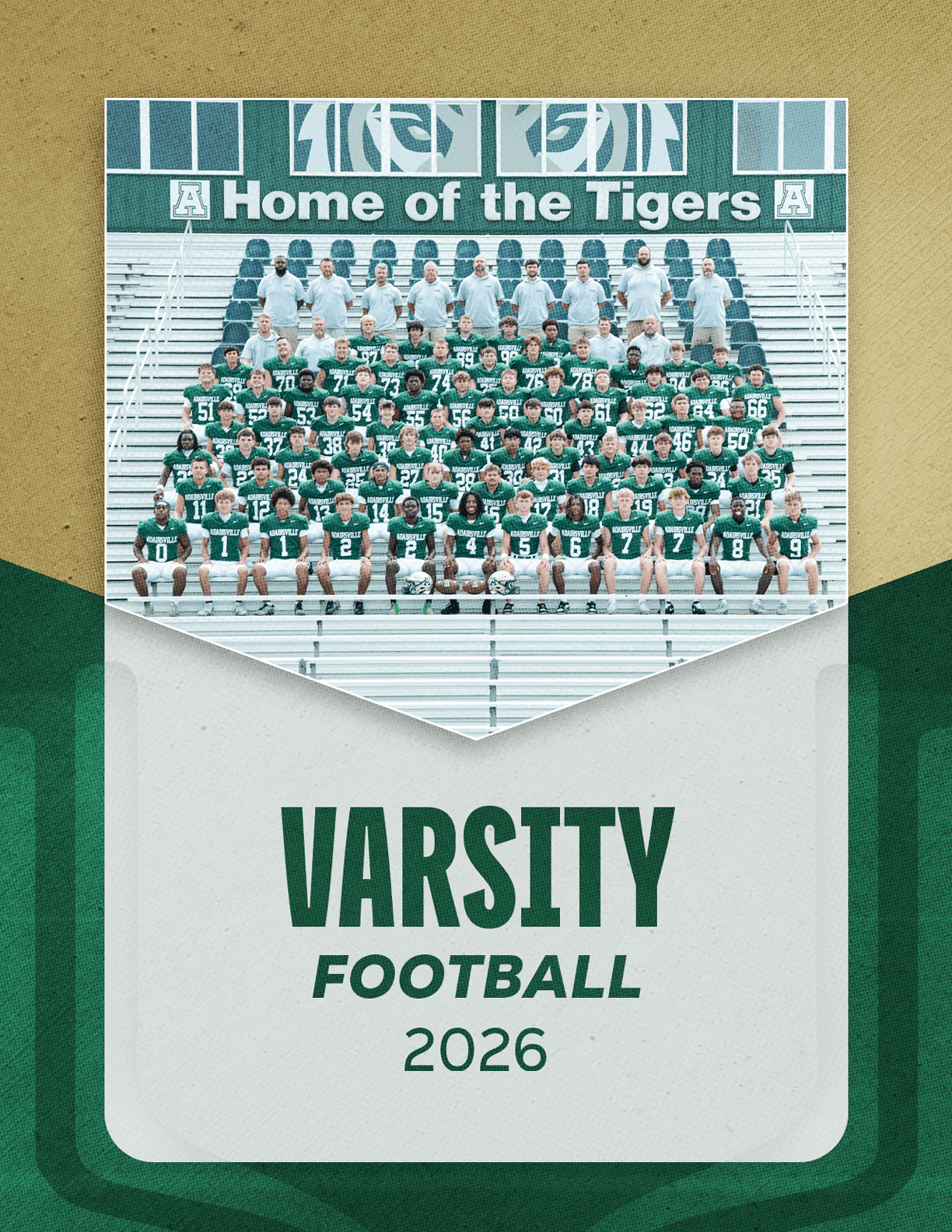 A large group of people in green and white football uniforms and gray shirts pose for a team photo on bleachers under a sign that reads Home of the Tigers with the text Varsity Football 2026 below. Description generated by AI