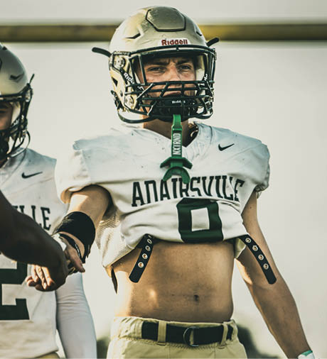 A person wearing a football helmet and a white jersey with the word “ANATRSVILLE" and the number zero on it is shown from the chest up. Description generated by AI