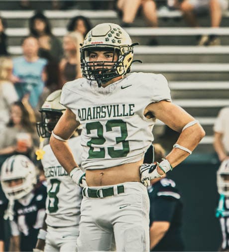A person wearing a football helmet and a white jersey with the word “ANATRSVILLE" and the number zero on it is shown from the chest up. Description generated by AI