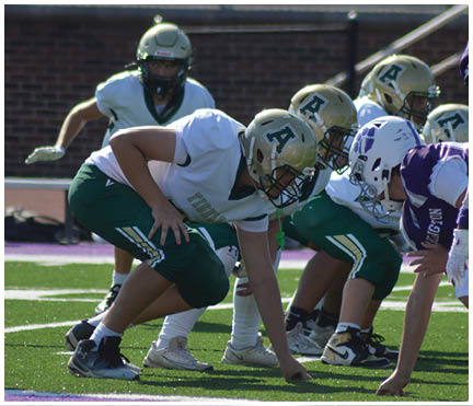 Several people in athletic shoes and sportswear are crouched in a starting position on a green field with white and purple markings. Description generated by AI