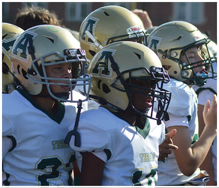 People wearing white sports jerseys with green and yellow lettering and numbers are standing close together. Description generated by AI