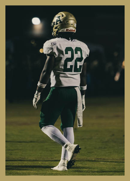 A person wearing a football uniform with the number 22 on the back is standing on a field at night. Description generated by AI