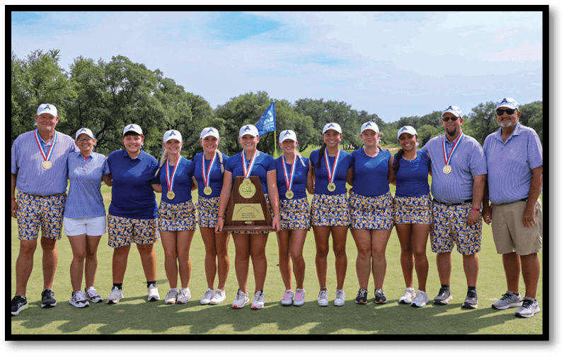A group of people wearing matching blue shirts and patterned shorts stand on a golf course with medals around their necks and one person holding a large trophy. Description generated by AI