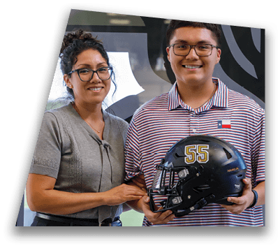 A person wearing glasses and a striped polo shirt with a small flag patch is smiling and holding a black helmet with the number 55 on it. Description generated by AI