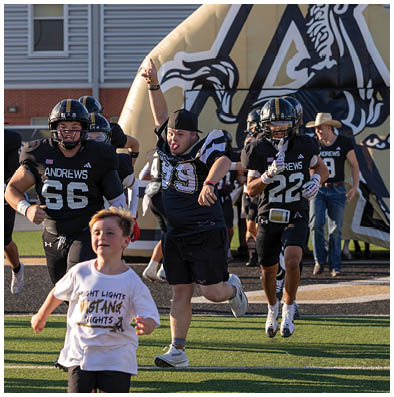 Two people in football uniforms are running on a field, with one person playfully sticking out their tongue and raising an arm. Description generated by AI