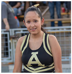 A person wearing a black and gold cheerleading uniform stands on a track with bracelets on both wrists. Description generated by AI