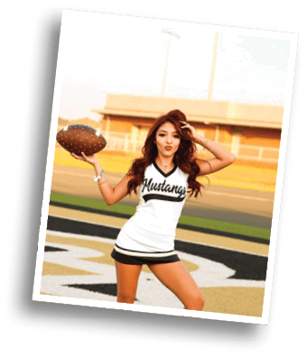 Person with long wavy hair wearing a white sports jersey with black trim and the word Mustangs written on it is posing outdoors. Description generated by AI