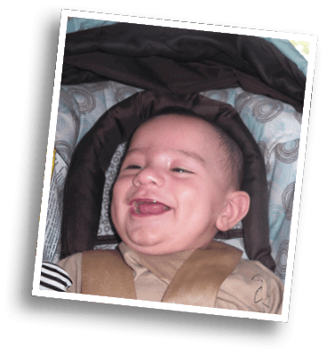 A smiling child wearing a brown outfit is lying on a patterned cushion with circular designs. Description generated by AI