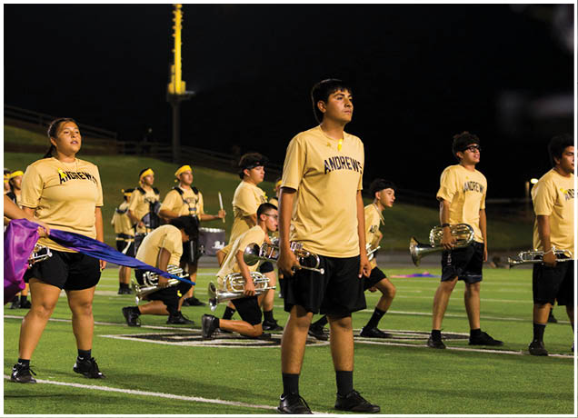 A person wearing a yellow shirt is looking up under a bright stadium light at night. Description generated by AI