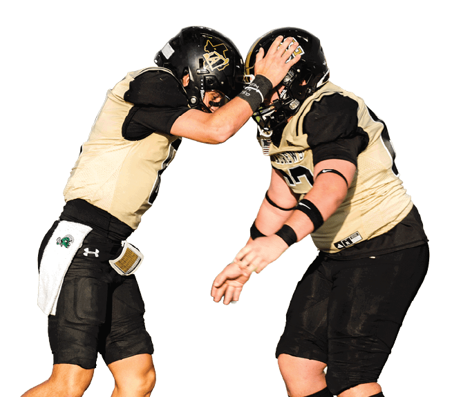 Two people wearing football uniforms and helmets are touching their helmets together on a field with a blurred background. Description generated by AI